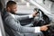 Smiling black businessman turning on music in his car