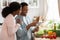 Smiling Black Couple Using Digital Tablet While Cooking In Kitchen, Searching Recipe