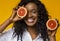 Smiling black girl holding two halves of grapefruit