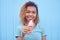 Smiling black girl with pink melting ice cream at blue wall background