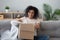 Smiling black girl unpack parcel at home shopping online