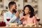 Smiling black guy feeding his happy woman with pasta