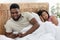 Smiling black man chatting with lover while wife sleeping