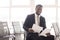 Smiling black man with papers on chair