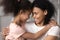 Smiling black mother and daughter look in eyes hugging