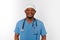 Smiling black surgeon doctor bearded man in blue coat, medical cap with stethoscope isolated white