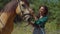 Smiling black woman caressing horse head outdoors