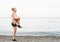 Smiling blond athlete woman doing stretching warming up before training on the seaside