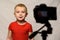 Smiling blond boy in front of the camera lens. Little video blogger. Home studio