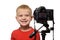 Smiling blond boy in front of the camera lens. Little video blogger. White background