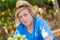 Smiling blond boy in hat harvesting ripe grapes