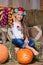 Smiling blond girl with long hair in a colorful Ukrainian wreath and in embroidered is sitting on haystacks. Autumn decor, harvest