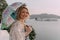 Smiling blond woman wearing a lace top holding a parasol umbrella overlooking Pichola Lake in Udaipur India