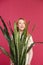 Smiling blonde holding flower sansevieria on pink background