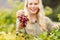 Smiling blonde winegrower holding a red grape