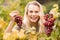 Smiling blonde winegrower holding red grapes