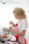 Smiling blonde woman cooking cupcakes in kitchen