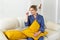 Smiling blonde woman sitting on comfortable coach in living room in pajama copy space - homewear and free time holidays