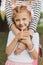 Smiling blue-eyed girl standing near her caring parent