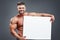 Smiling bodybuilder holding blank white poster