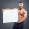 Smiling bodybuilder holding blank white poster