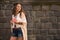 Smiling boho young woman near stone wall looking on copy space