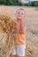 The smiling boy collects a harvest of wheat spikes. Happy little boy having fun in the golden field.