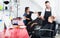 Smiling boy getting hairdo in crowded beauty salon