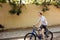 Smiling boy happily riding bicycle. Young cheerful man with blond hair having fun while riding on blue bicycle along