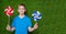 Smiling boy holding pinwheels over grass