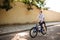 Smiling boy joyfully riding bicycle. Young cheerful man with blond hair having fun while riding on blue bicycle along