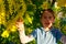 A smiling boy playing with yellow balls of Mimosa tree. South France holidays. Spring is coming. Early bloom