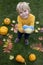 smiling boy standing among orange pumpkins and autumn leaves holds out yellow-blue Ukrainian heart