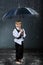 Smiling boy standing under umbrella in rain