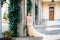 Smiling bride in a dress with a bouquet of pink flowers leaning against a pillar in a vaulted room. Lake Como, Italy