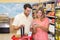 Smiling bright couple buying food products with shopping basket