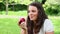 Smiling brunette haired woman eating a red apple