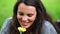 Smiling brunette holding while smelling a flower