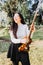 Smiling brunette woman with glasses tuning her violin in the park. Vertical.