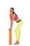 Smiling brunette woman in sports neon yellow leggings and pink bra leaning on the rolled orange mat