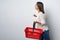 Smiling brunette woman walking with empty shopping basket