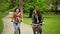 Smiling Brunettes on the Bicycles are Riding in the Park During the Spring.Two Active Young Women Wearing Jackets and