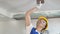 Smiling builder female in hardhat sanding wall indoors at construction site