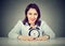 Smiling business woman with alarm clock sitting at table