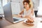 Smiling business woman drinking coffee with cookies on workplace