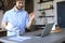 Smiling businessman greeting colleagues in video conference and negotiating distantly from home