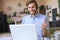 Smiling businessman greeting colleagues in video conference and negotiating distantly from home