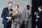 Smiling businessman presenting flowers to businesswoman with multiethnic colleagues on background in