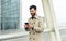 Smiling businessman with smartphone in airport. Young businessman typing text message on his way to work