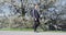 Smiling Businessman Using Smartphone While Walking By Flowering Tree In Park